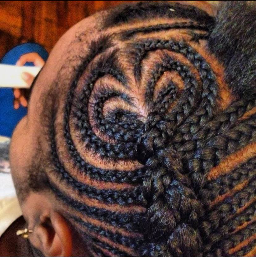 Close-up view of intricate curved cornrows and braided heart details